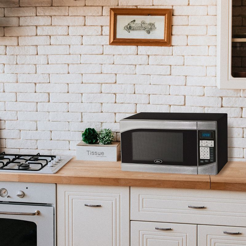 Oster 0.9 Cubic Feet 900-Watt Countertop Microwave Oven in Black and Silver